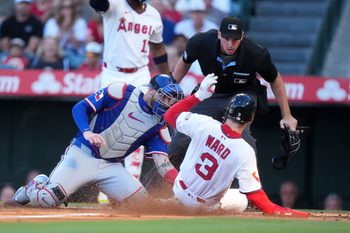 Jul 10, 2025; Anaheim, California, USA; Los Angeles Angels left fielder Taylor Ward (3) is tagged out at home plate by Texas Rangers catcher Jonah Heim (28) as home plate umpire Nate Tomlinson makes the call in the first inning at Angel Stadium. Mandatory Credit: Kirby Lee-Imagn Images