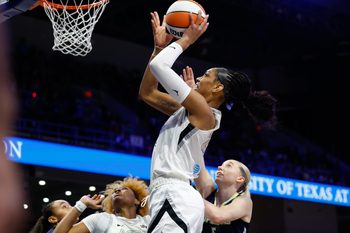 Jul 16, 2025; Arlington, Texas, USA;Las Vegas Aces center A'ja Wilson (22) scores a layup past Dallas Wings guard Paige Bueckers (5)  during the first half at College Park Center. Mandatory Credit: Chris Jones-Imagn Images