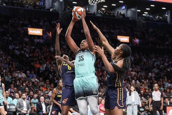 Jul 22, 2025; Brooklyn, New York, USA;  New York Liberty center Jonquel Jones (35) jumps in front of Indiana Fever forwards Natasha Howard (6) and Aliyah Boston (7) to grab a rebound in the first quarter at Barclays Center. Mandatory Credit: Wendell Cruz-Imagn Images