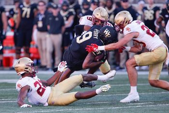 Oct 22, 2022; Winston-Salem, North Carolina, USA;  Boston College Eagles defensive back Josh DeBerry (bottom left) and defensive back Cole Batson (right) and defensive back Jaiden Woodbey (9) tackle Wake Forest Demon Deacons wide receiver A.T. Perry (9) during the second quarter at Truist Field. Mandatory Credit: Reinhold Matay-Imagn Images