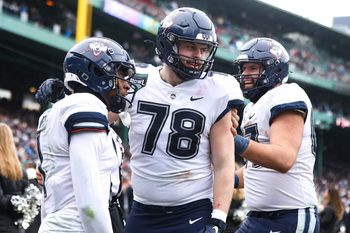 UConn's Skyler Bell, left, celebrates a touchdown with teammates Carsten Casady, center, and Christopher Fortin during the third annual Wasabi Fenway Bowl against North Carolina at Fenway Park on Saturday, Dec. 28, 2024.