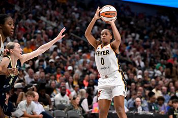 Aug 1, 2025; Dallas, Texas, USA;  Indiana Fever guard Kelsey Mitchell (0) makes a jump shot over Dallas Wings guard Paige Bueckers (5) during the second half at the American Airlines Center. Mandatory Credit: Jerome Miron-Imagn Images