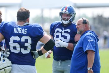 Aug 4, 2025; East Rutherford, NJ, USA; New York Giants center Austin Schlottmann (65) talks with guard Jake Kubas (63) and offensive line coach Carmen Bricillo during training camp at Quest Diagnostics Training Center. Mandatory Credit: Vincent Carchietta-Imagn Images
