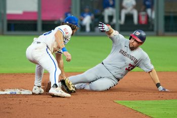Aug 11, 2025; Kansas City, Missouri, USA; Kansas City Royals second baseman Adam Frazier (26) misses the tag as Washington Nationals first baseman Nathaniel Lowe (33) reaches second base on a double in the fifth inning at Kauffman Stadium. Mandatory Credit: Denny Medley-Imagn Images