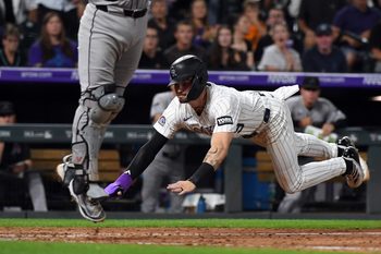 Aug 16, 2025; Denver, Colorado, USA; Colorado Rockies outfielder Brenton Doyle (9) slides safely into home ahead of the tag by Arizona Diamondbacks catcher Adrian Del Castillo (25) during the eighth inning at Coors Field. Mandatory Credit: Christopher Hanewinckel-Imagn Images