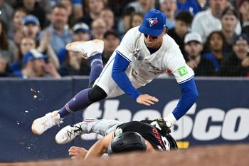 Aug 26, 2025; Toronto, Ontario, CAN;  Toronto Blue Jays third baseman Ernie Clement (22) is upended after tagging out Minnesota Twins right fielder Matt Wallner (38) in the eighth inning at Rogers Centre. Mandatory Credit: Dan Hamilton-Imagn Images