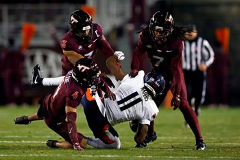 Nov 30, 2024; Blacksburg, Virginia, USA; Virginia Cavaliers wide receiver Trell Harris (11) is tackled by Virginia Tech Hokies cornerback Mansoor Delane (4) and linebacker Keonta Jenkins (7) during the fourth quarter at Lane Stadium. Mandatory Credit: Peter Casey-Imagn Images