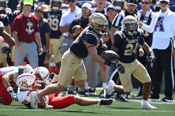 Aug 30, 2025; Annapolis, Maryland, USA; Navy Midshipmen running back Alex Tecza (46) breaks out of a tackle by Virginia Military Institute Keydets defensive back EJ Wilborne (14) during the third quarter at Navy-Marine Corps Memorial Stadium. Mandatory Credit: Rafael Suanes-Imagn Images
