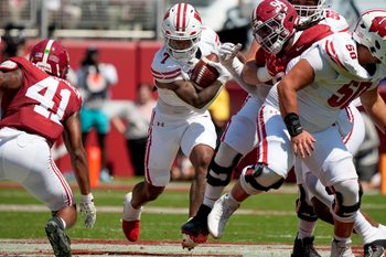 Sep 13, 2025; Tuscaloosa, Alabama, USA;  Wisconsin running back Dilin Jones (7) runs the ball between Alabama linebacker Nikhai Hill-Green (41) and Alabama defensive lineman Edric Hill (94) at Saban Field at Bryant-Denny Stadium. Mandatory Credit: Gary Cosby-USA TODAY Network via Imagn Images