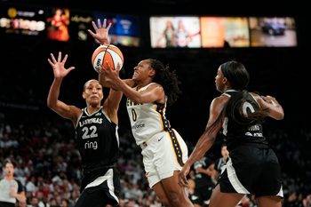 Sep 21, 2025; Las Vegas, Nevada, USA; Indiana Fever guard Kelsey Mitchell (0) attempts to score a layup against Las Vegas Aces center A'ja Wilson (22) and guard Jackie Young (0) during the second quarter in game one of the second round for the 2025 WNBA Playoffs at Michelob Ultra Arena. Mandatory Credit: Lucas Peltier-Imagn Images