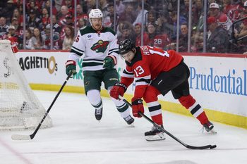 Mar 31, 2025; Newark, New Jersey, USA; New Jersey Devils center Nico Hischier (13) plays the puck against Minnesota Wild defenseman Jonas Brodin (25) during the second period at Prudential Center. Mandatory Credit: Ed Mulholland-Imagn Images