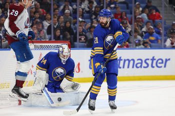 Oct 13, 2025; Buffalo, New York, USA;  Buffalo Sabres goaltender Alex Lyon (34) makes a save as Colorado Avalanche center Nathan MacKinnon (29) and Buffalo Sabres defenseman Conor Timmins (21) wait for a rebound during the third period at KeyBank Center. Mandatory Credit: Timothy T. Ludwig-Imagn Images