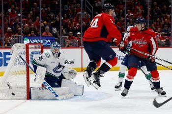 Oct 19, 2025; Washington, District of Columbia, USA; Vancouver Canucks goaltender Thatcher Demko (35) makes a save in front of Washington Capitals defenseman John Carlson (74) and Capitals center Aliaksei Protas (21) during the third period at Capital One Arena. Mandatory Credit: Geoff Burke-Imagn Images