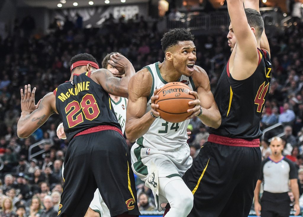 Dec 14, 2019; Milwaukee, WI, USA; Milwaukee Bucks forward Giannis Antetokounmpo (34) drives for the basket between Cleveland Cavaliers forward Alfonzo McKinnie (28) and center Ante Zizic (41) in the fourth quarter at Fiserv Forum. Mandatory Credit: Benny Sieu-Imagn Images