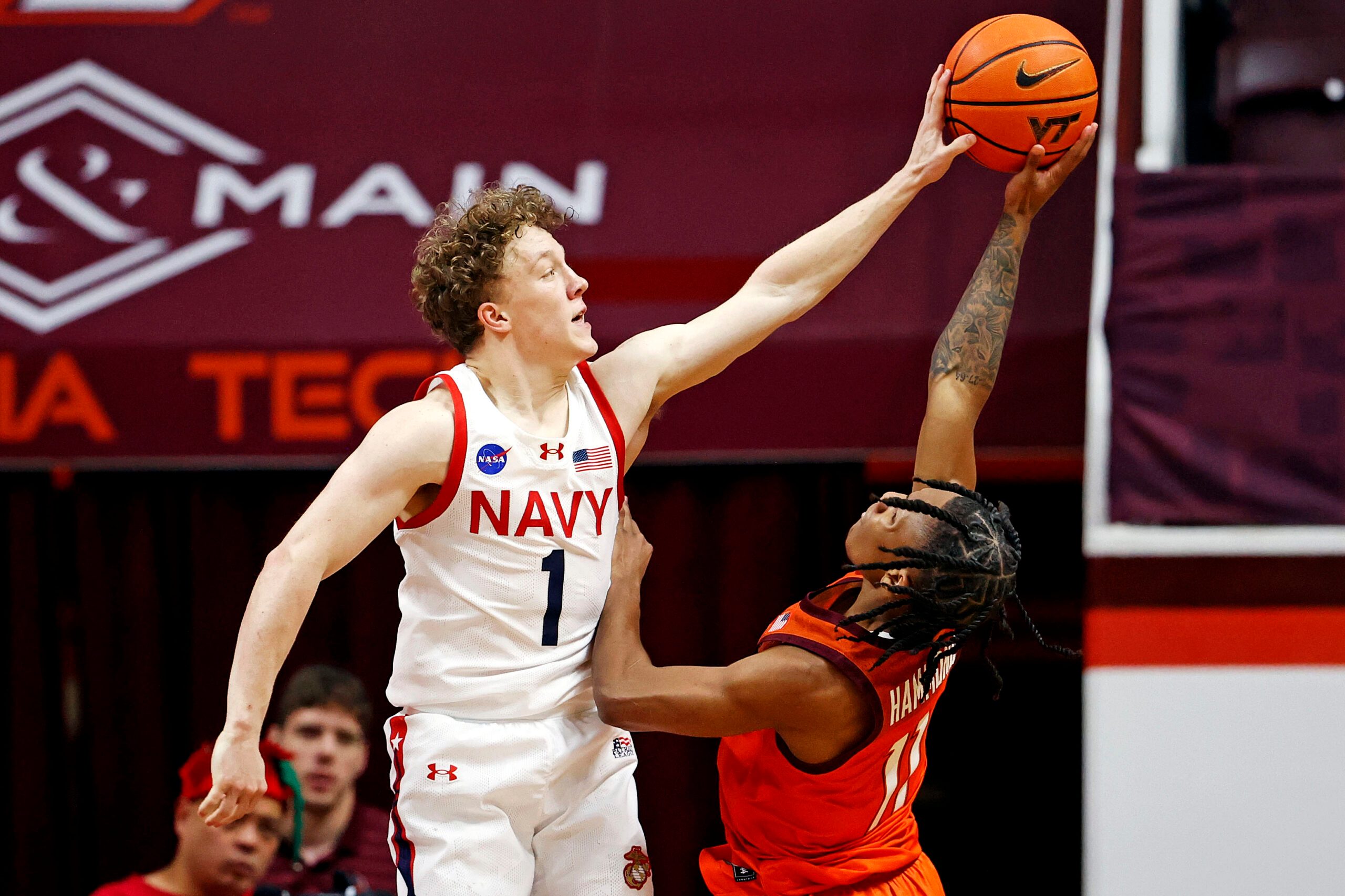 Dec 15, 2024; Blacksburg, Virginia, USA; Navy Midshipmen guard Austin Benigni (1) blocks the shot of Virginia Tech Hokies guard Ben Hammond (11) during the second half at Cassell Coliseum. Mandatory Credit: Peter Casey-Imagn Images