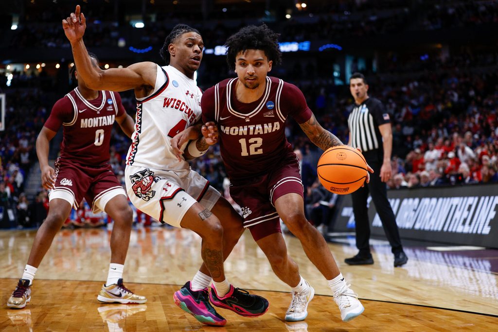 Mar 20, 2025; Denver, CO, USA; Wisconsin Badgers guard Kamari McGee (4) defends against Montana Grizzlies guard Brandon Whitney (12) during the second half in the first round of the NCAA Tournament at Ball Arena. Mandatory Credit: Isaiah J. Downing-Imagn Images