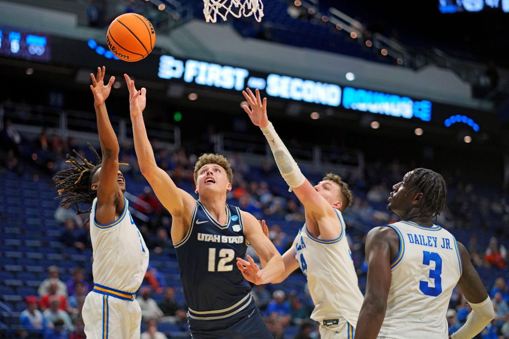 Mar 20, 2025; Lexington, KY, USA; Utah State Aggies guard Mason Falslev (12) shoots the ball against UCLA Bruins forward Tyler Bilodeau (34) during the second half in the first round of the NCAA Tournament at Rupp Arena. Mandatory Credit: Aaron Doster-Imagn Images