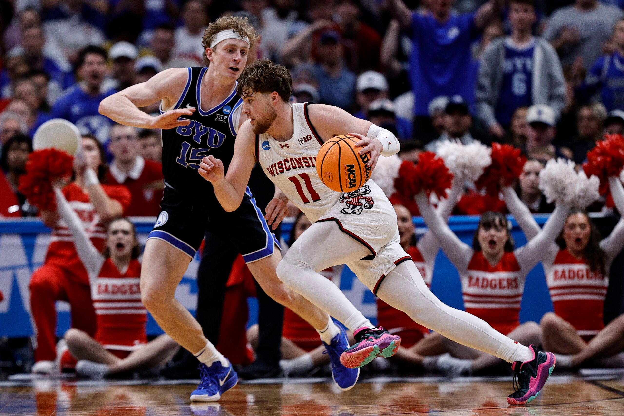 Mar 22, 2025; Denver, CO, USA; Wisconsin Badgers guard Max Klesmit (11) dribbles the ball past Brigham Young Cougars forward Richie Saunders (15) during the second half in the second round of the NCAA Tournament  at Ball Arena. Mandatory Credit: Isaiah J. Downing-Imagn Images