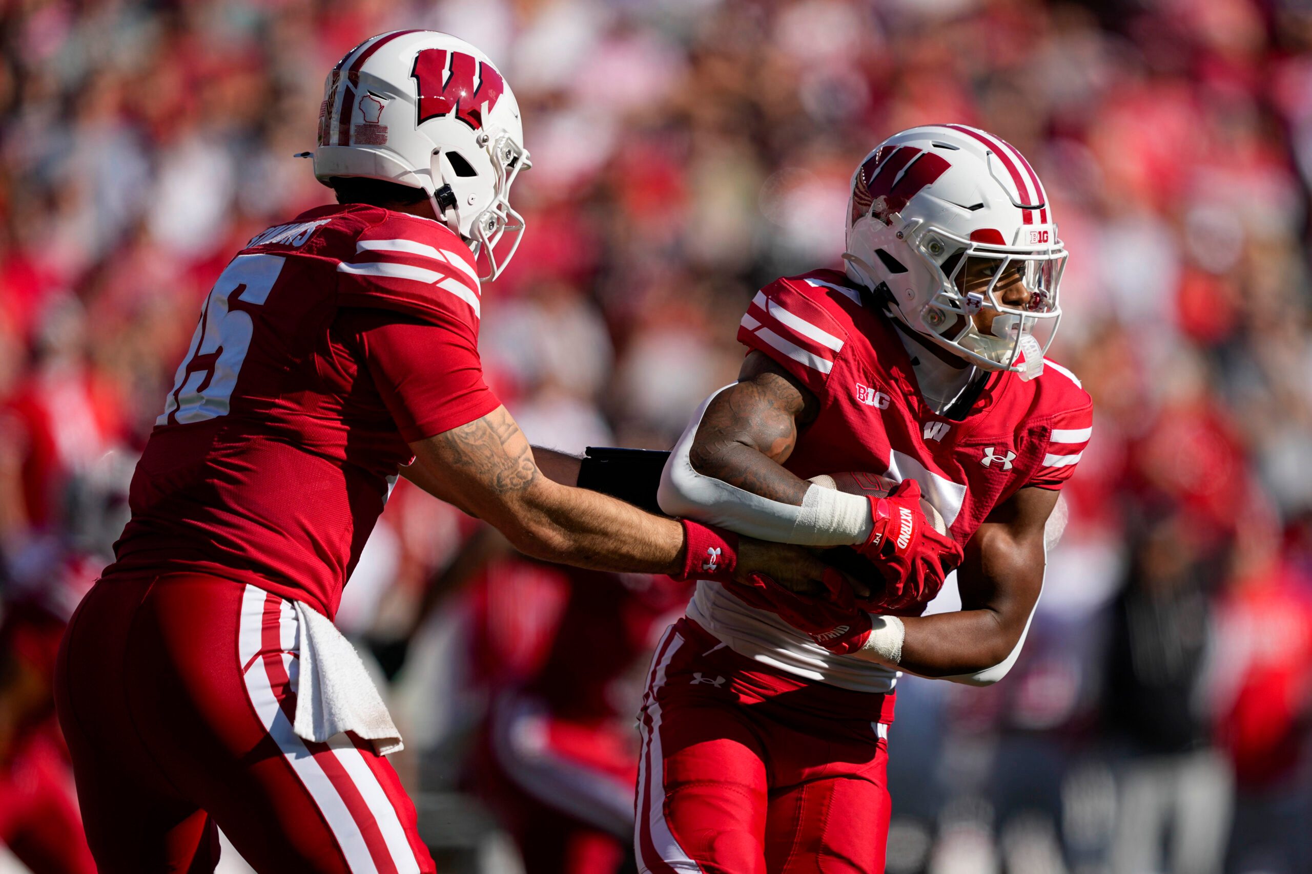 Oct 18, 2025; Madison, Wisconsin, USA;  Wisconsin Badgers quarterback Hunter Simmons (15) hands the football off to running back Dilin Jones (7) during the game against the Ohio State Buckeyes at Camp Randall Stadium. Mandatory Credit: Jeff Hanisch-Imagn Images