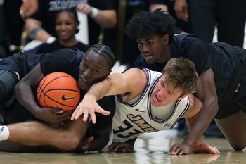 Akron Zips wing Marvin Musiime-Kamali (23) and guard Eric Mahaffey (4) wrestle for possession with James Madison Dukes forward Gabe Newhof (33) during the second half of an NCAA college basketball game at James A. Rhodes Arena, Nov. 3, 2025, in Akron, Ohio