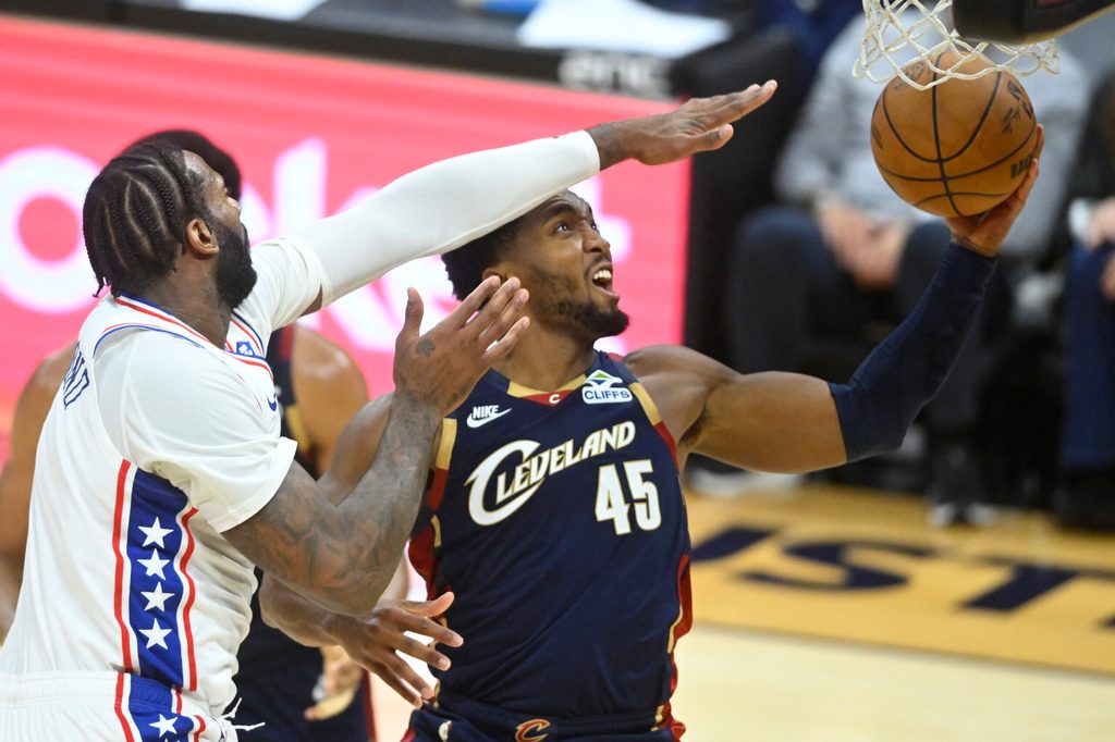 Nov 5, 2025; Cleveland, Ohio, USA; Cleveland Cavaliers guard Donovan Mitchell (45) drives to the basket beside Philadelphia 76ers center Andre Drummond (1) in the fourth quarter at Rocket Arena. Mandatory Credit: David Richard-Imagn Images