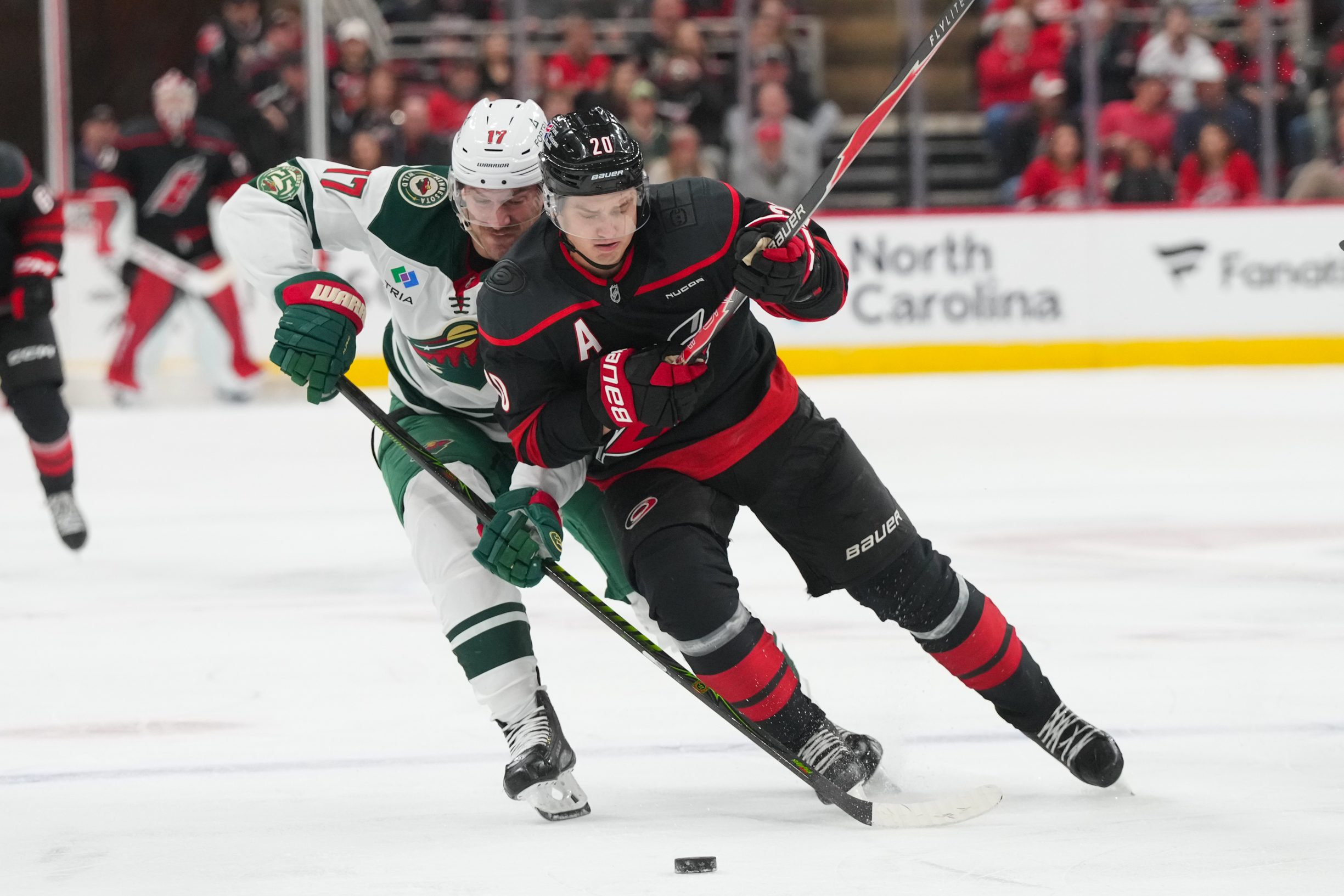 Nov 6, 2025; Raleigh, North Carolina, USA;  Carolina Hurricanes center Sebastian Aho (20) skates with the puck against Minnesota Wild left wing Marcus Foligno (17) during the third period at Lenovo Center. Mandatory Credit: James Guillory-Imagn Images