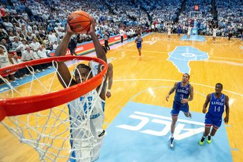 Nov 7, 2025; Chapel Hill, North Carolina, USA; North Carolina Tar Heels forward Caleb Wilson (8) dunks near the end of the second half as Kansas Jayhawks guard Tre White (3) and guard Melvin Council Jr. (14) are in the background at Dean E. Smith Center. Mandatory Credit: Bob Donnan-Imagn Images