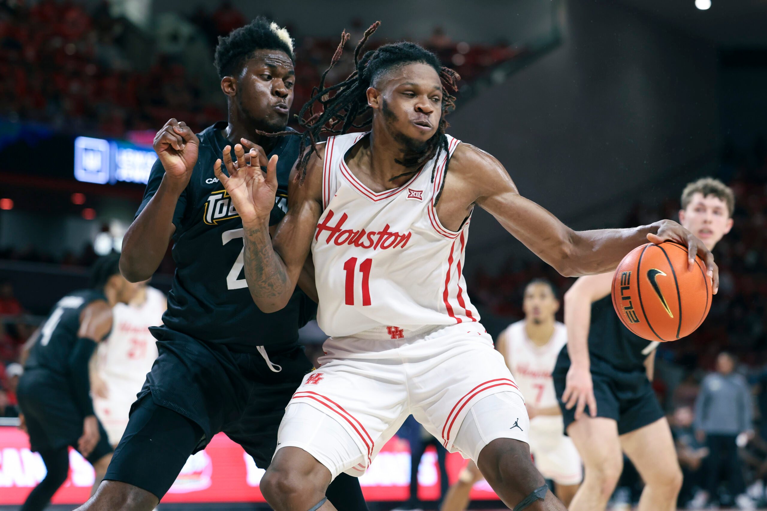 Nov 8, 2025; Houston, Texas, USA; Houston Cougars forward Joseph Tugler (11) attempts to control the ball as Towson Tigers forward Caleb Embeya (23) defends during the second half at Fertitta Center. Mandatory Credit: Troy Taormina-Imagn Images