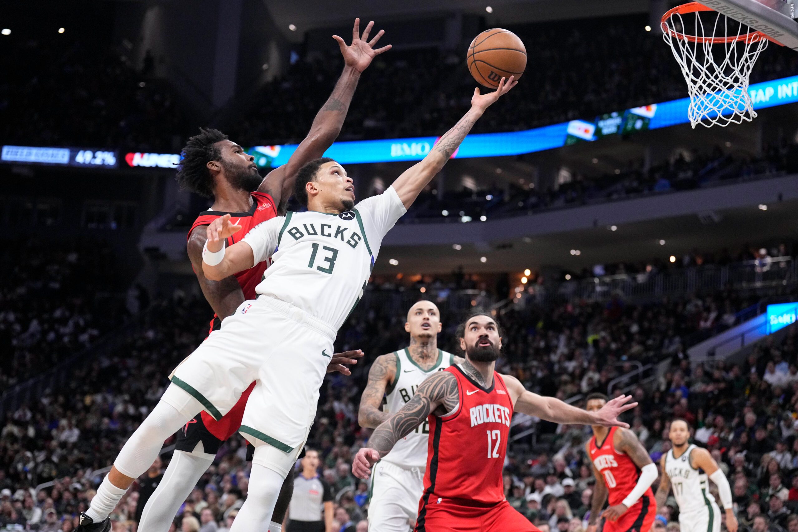 Nov 9, 2025; Milwaukee, Wisconsin, USA; Milwaukee Bucks guard Ryan Rollins (13) lays up a shot against Houston Rockets forward Tari Eason (17) in the second half at Fiserv Forum. Mandatory Credit: Michael McLoone-Imagn Images