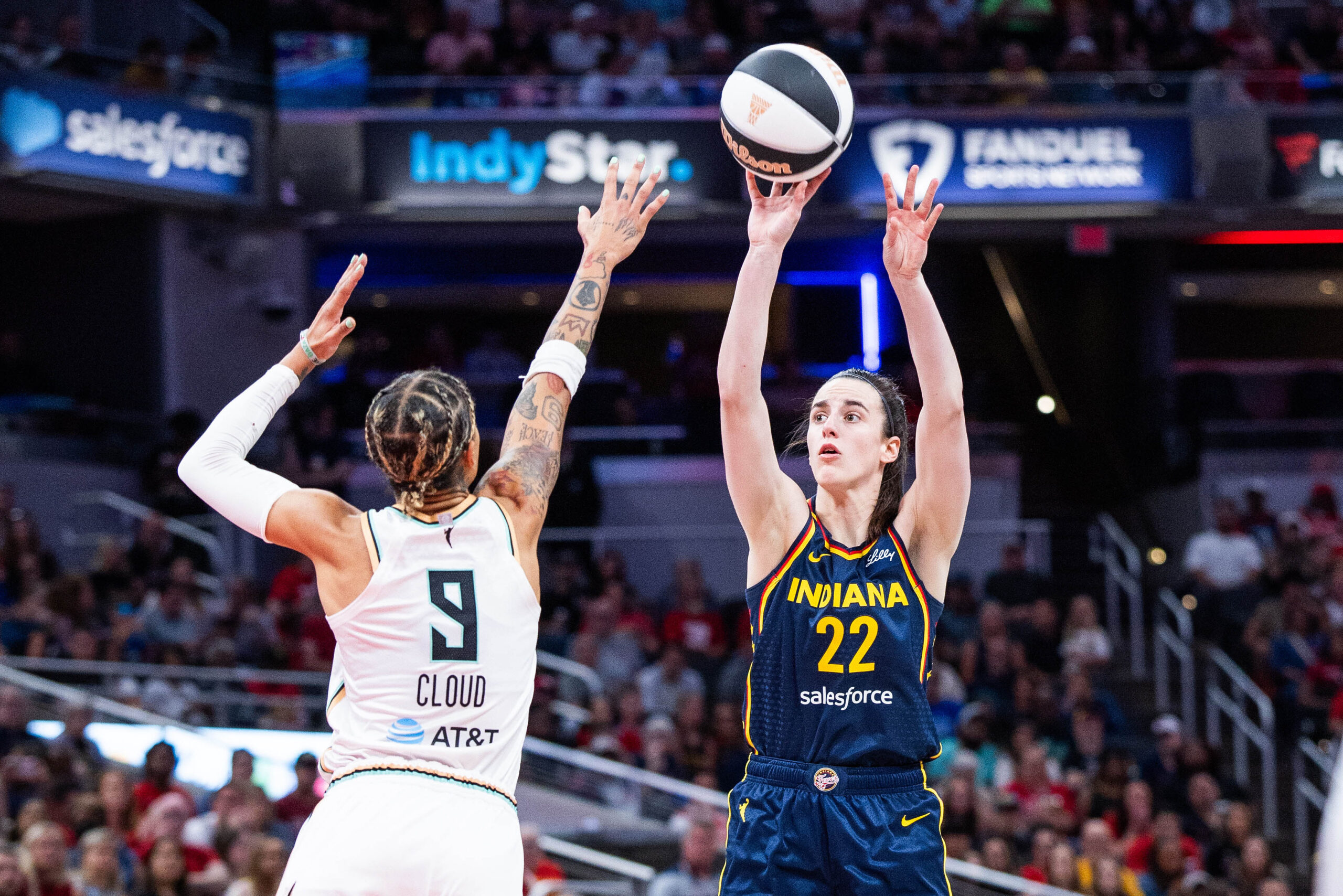 Jun 14, 2025; Indianapolis, Indiana, USA; Indiana Fever guard Caitlin Clark (22) shoots the ball while New York Liberty guard Natasha Cloud (9) defends in the first half at Gainbridge Fieldhouse. Mandatory Credit: Trevor Ruszkowski-Imagn Images