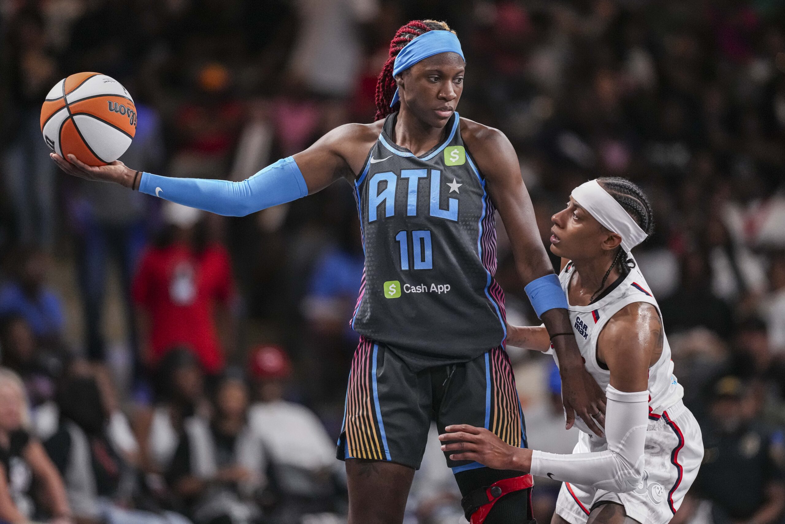 Jun 20, 2025; College Park, Georgia, USA; Atlanta Dream guard Rhyne Howard (10) protects the ball from Washington Mystics guard Brittney Sykes (20) during the first half at Gateway Center Arena at College Park. Mandatory Credit: Dale Zanine-Imagn Images