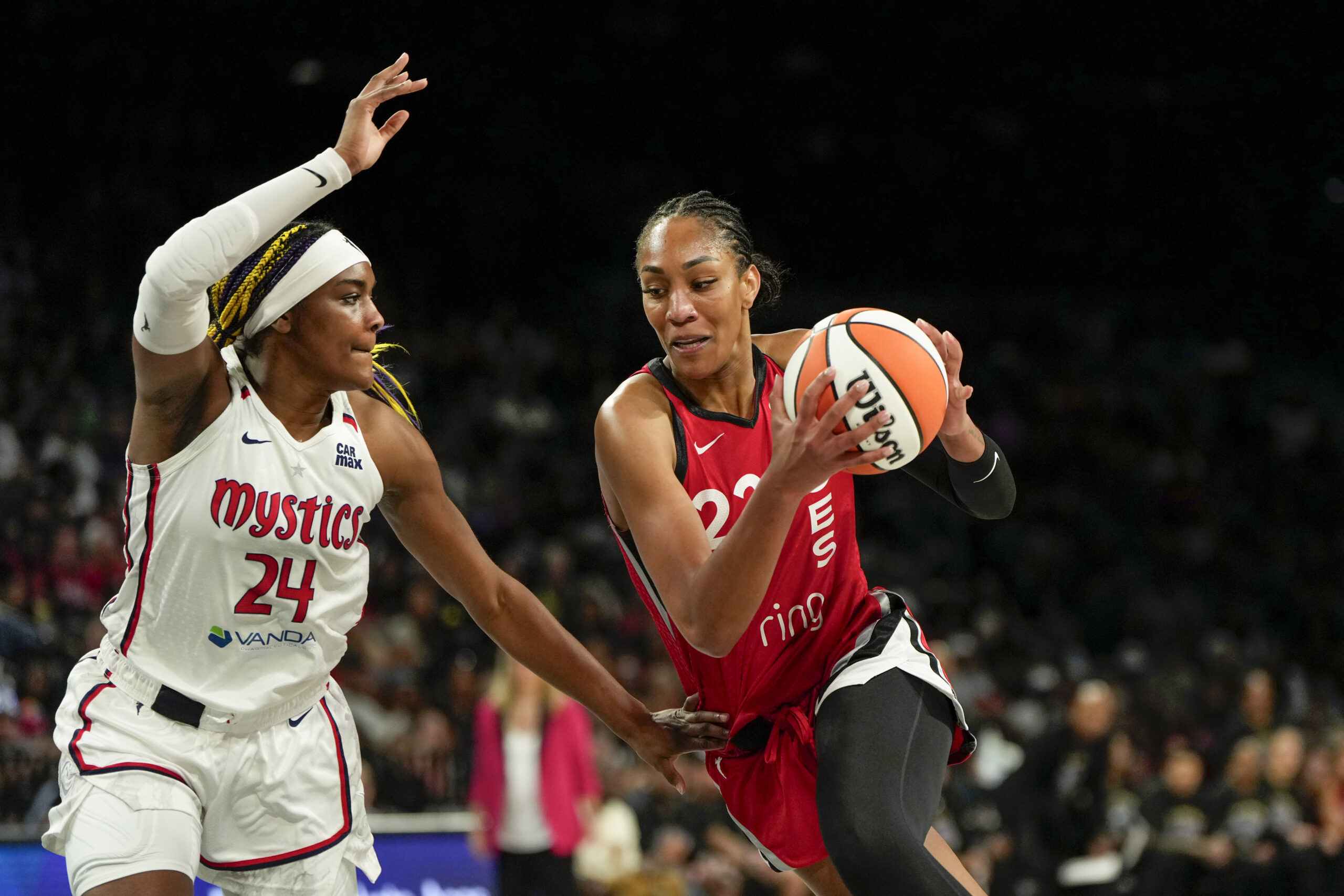 Jun 26, 2025; Las Vegas, Nevada, USA; Las Vegas center A'ja Wilson (22) drives the ball against Washington Mystics forward Aaliyah Edwards (24) during the first half of a WNBA basketball game at Michelob Ultra Arena. Mandatory Credit: Lucas Peltier-Imagn Images