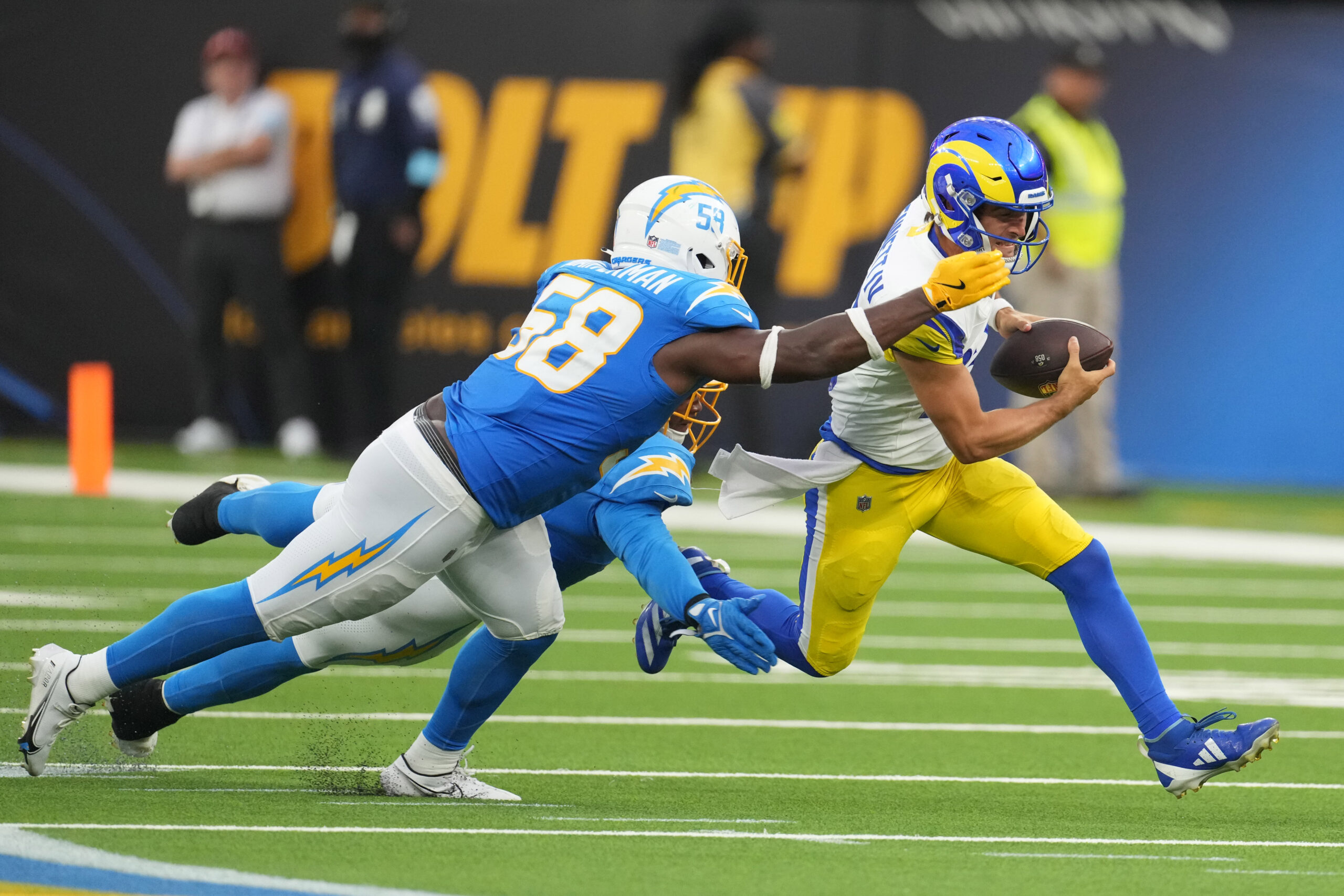 Aug 17, 2024; Inglewood, California, USA; Los Angeles Rams quarterback Stetson Bennett (13) carries the ball against Los Angeles Chargers linebacker Shaq Quarterman (58) in the second half at SoFi Stadium. Mandatory Credit: Kirby Lee-Imagn Images