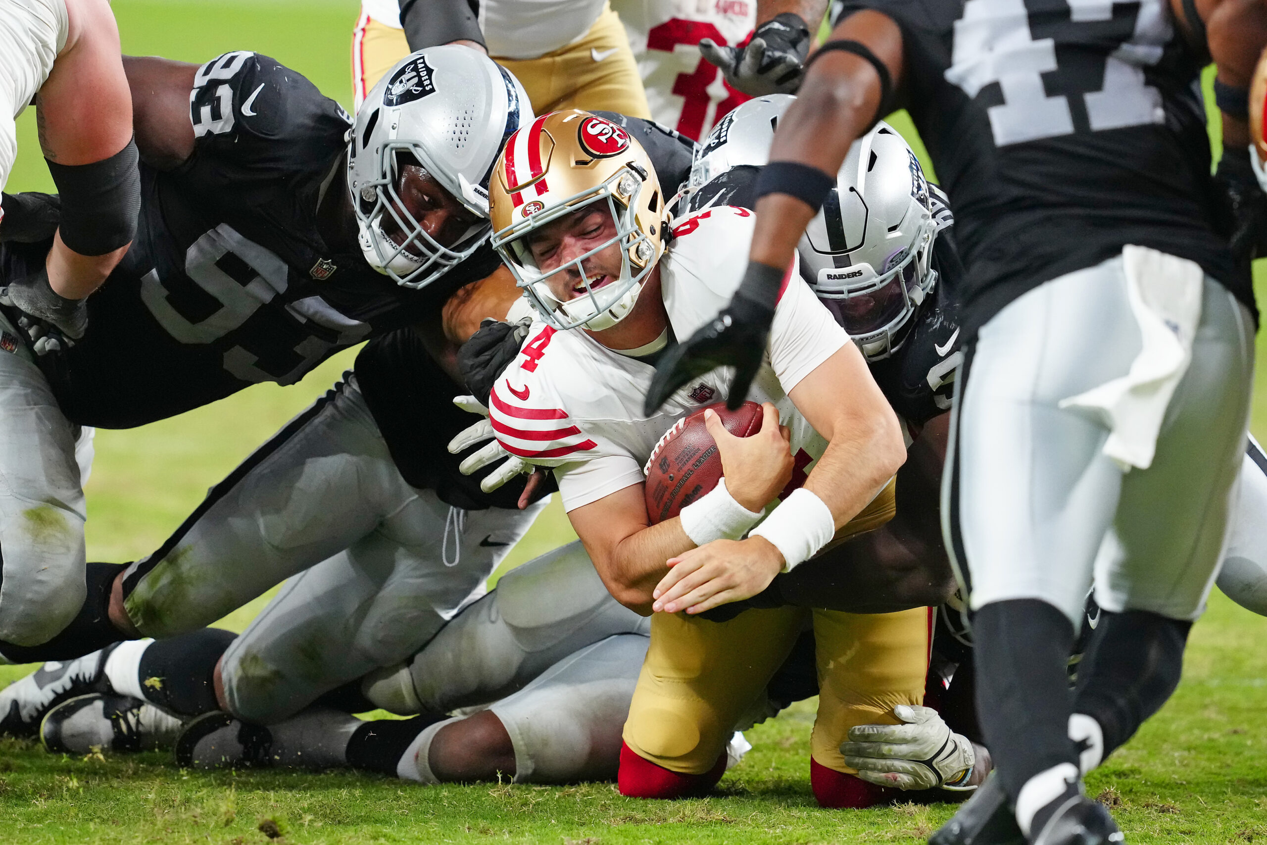 Aug 23, 2024; Paradise, Nevada, USA; San Francisco 49ers quarterback Tanner Mordecai (4) is tackled by Las Vegas Raiders players during the fourth quarter at Allegiant Stadium. Mandatory Credit: Stephen R. Sylvanie-Imagn Images