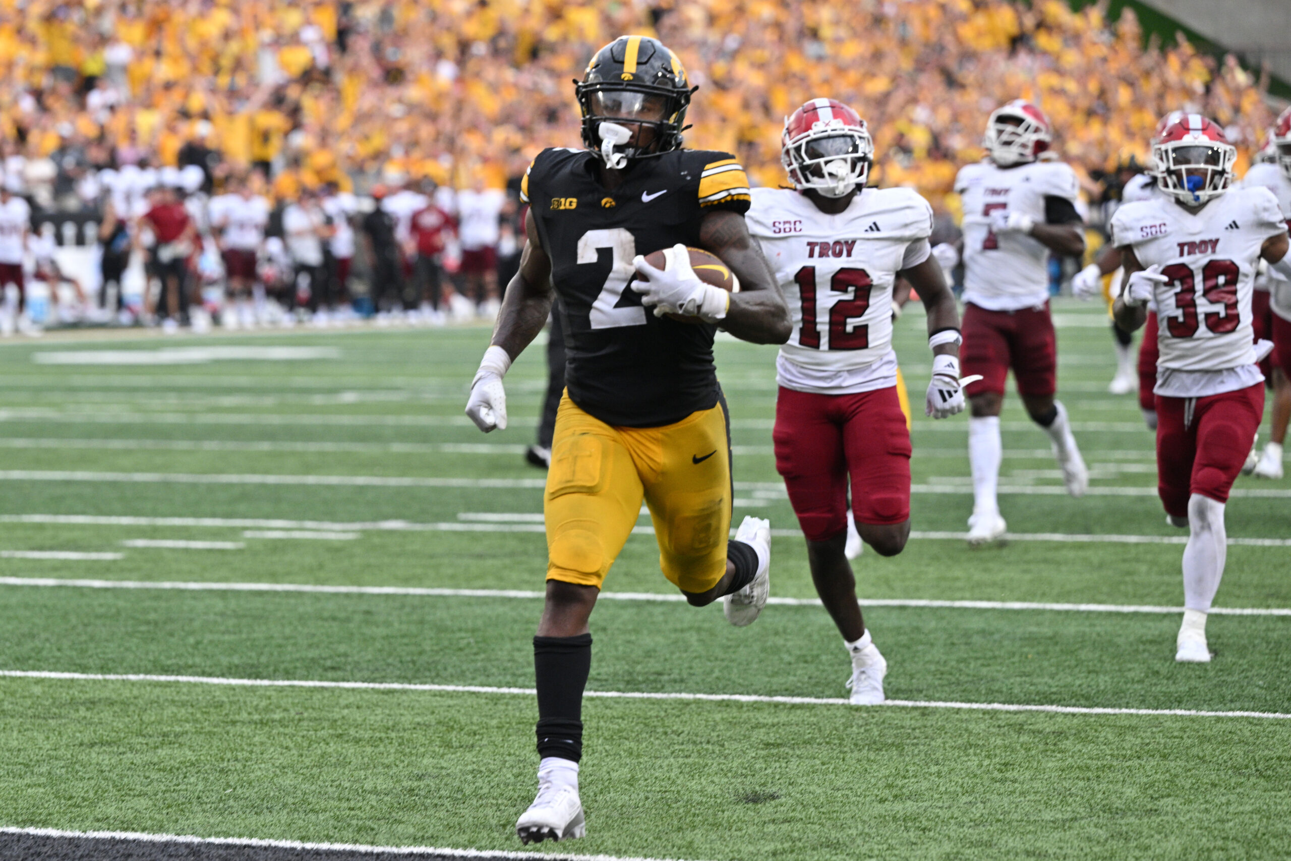 Sep 14, 2024; Iowa City, Iowa, USA; Iowa Hawkeyes running back Kaleb Johnson (2) scores on a 33 yard run as Troy Trojans cornerback Trent Henry (12) and safety Ian Conerly-Goodly (39) pursue during the fourth quarter at Kinnick Stadium. Mandatory Credit: Jeffrey Becker-Imagn Images