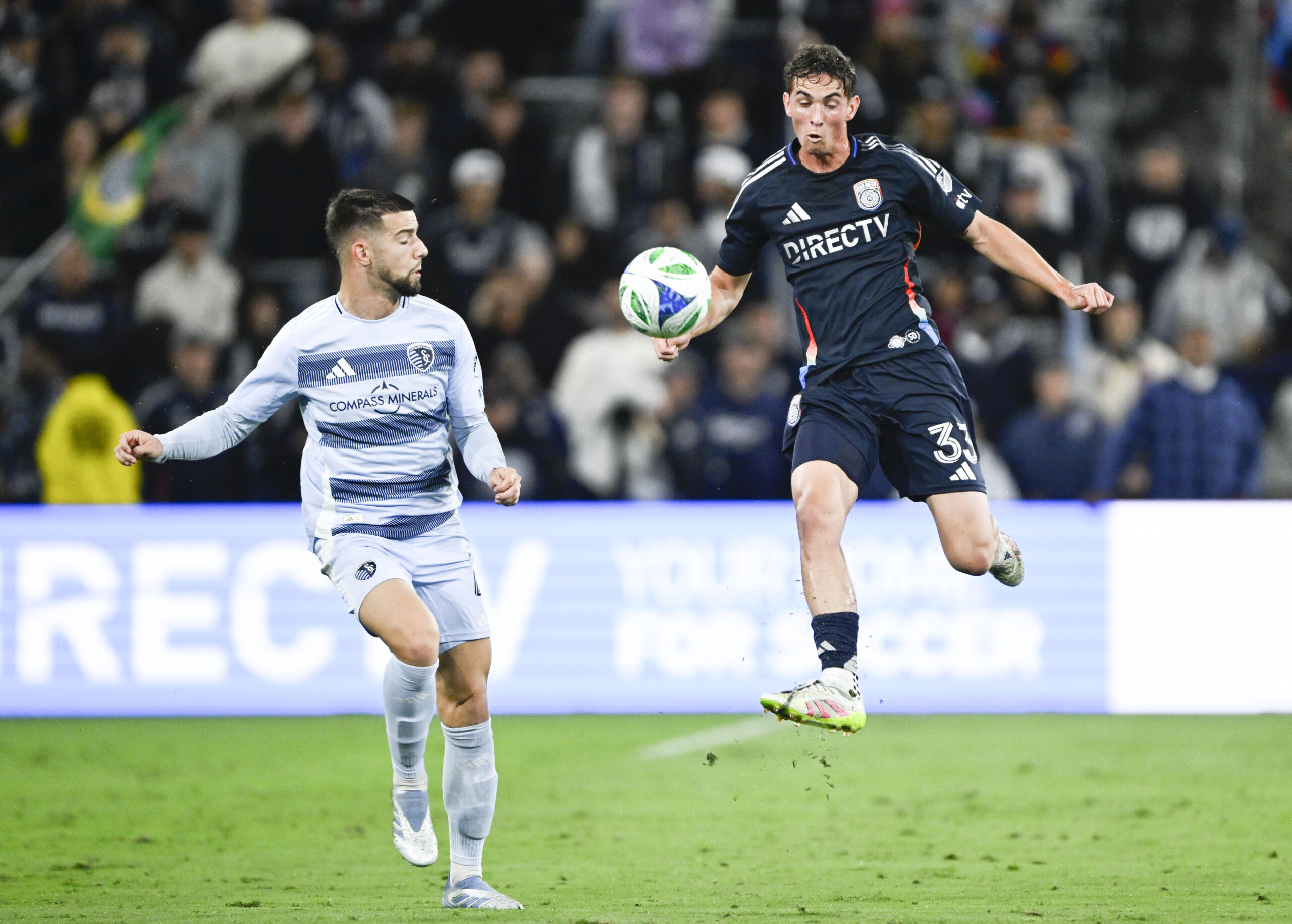 May 17, 2025; San Diego, California, USA; San Diego FC defender Oscar Verhoeven (33) fights for the ball with Sporting Kansas City defender Robert Voloder (4) during the first half at Snapdragon Stadium. Mandatory Credit: Denis Poroy-Imagn Images