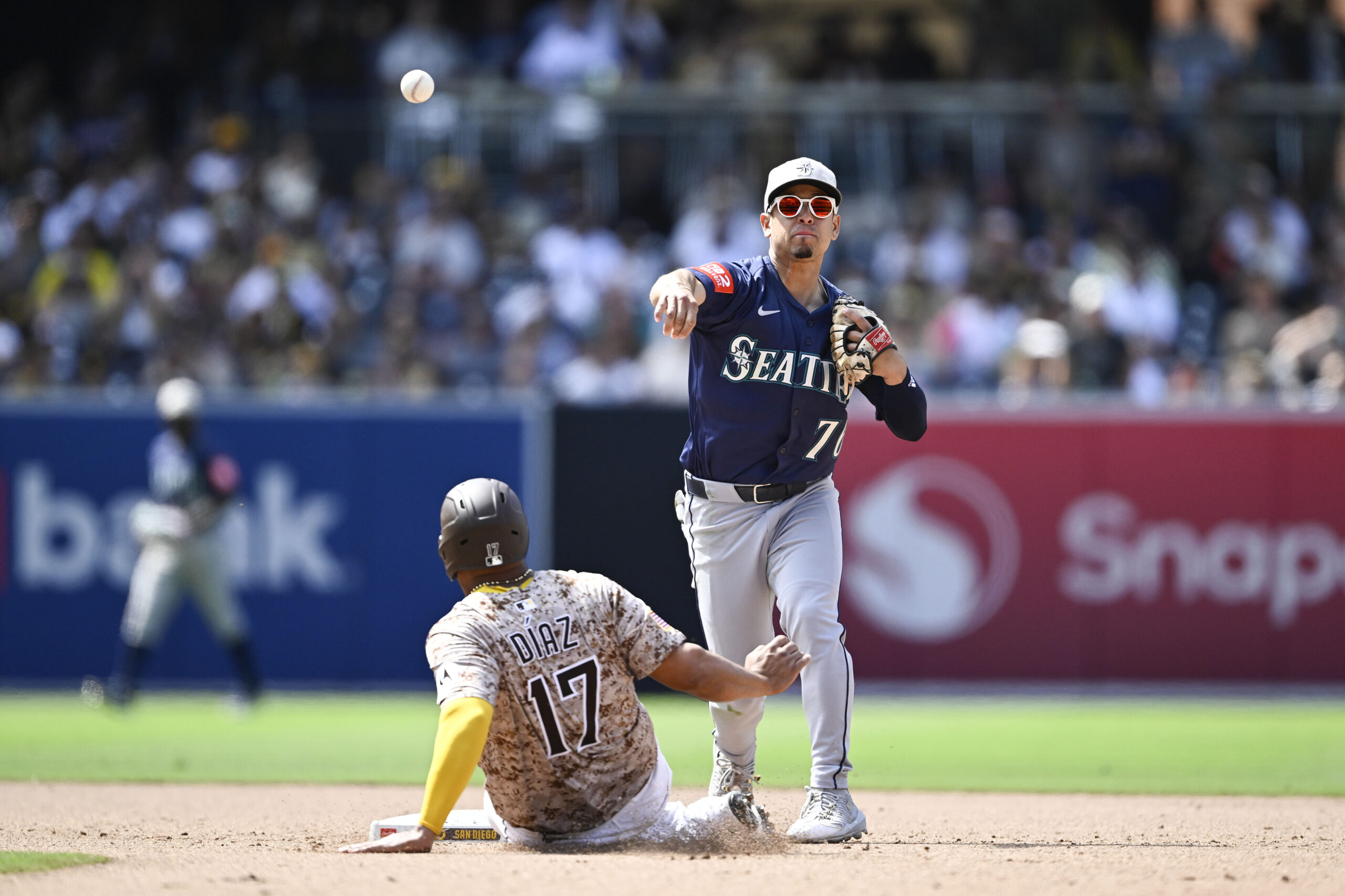 May 18, 2025; San Diego, California, USA; Seattle Mariners second baseman Leo Rivas (76) throws over San Diego Padres catcher Elias Diaz (17) as he turns a double play during the eighth inning at Petco Park. Mandatory Credit: Denis Poroy-Imagn Images