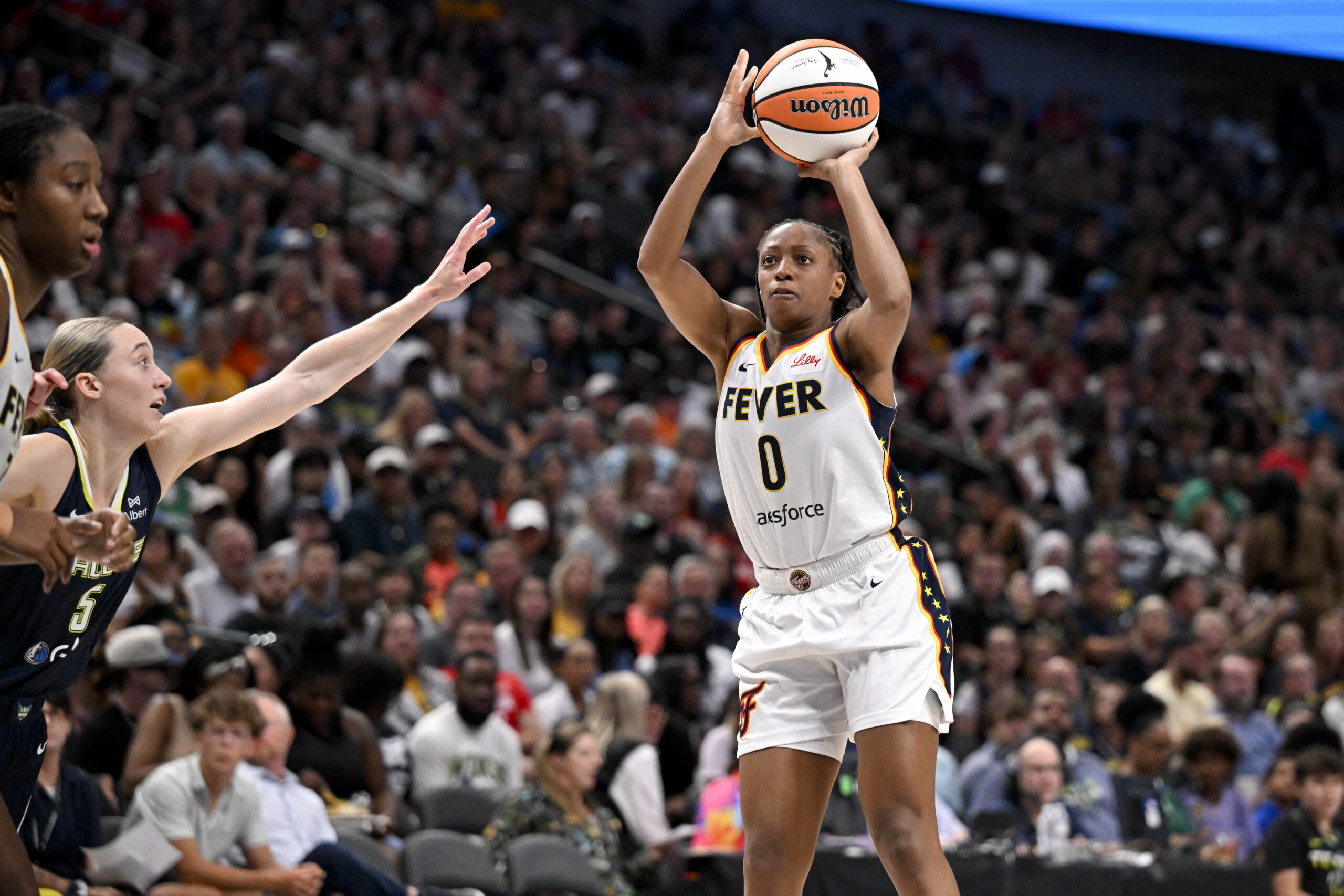 Aug 1, 2025; Dallas, Texas, USA;  Indiana Fever guard Kelsey Mitchell (0) makes a jump shot over Dallas Wings guard Paige Bueckers (5) during the second half at the American Airlines Center. Mandatory Credit: Jerome Miron-Imagn Images