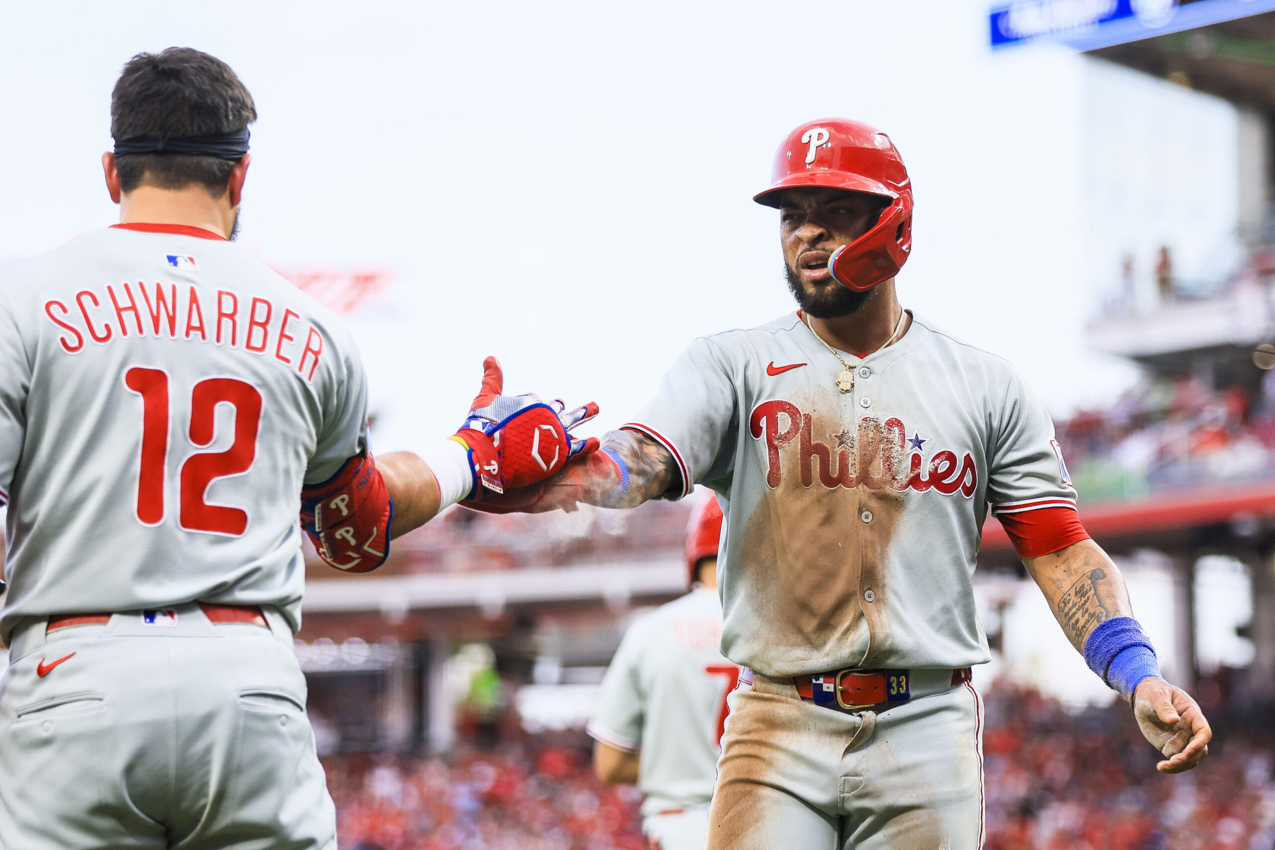 Aug 11, 2025; Cincinnati, Ohio, USA; Philadelphia Phillies second baseman Edmundo Sosa (33) high fives designated hitter Kyle Schwarber (12) after scoring on a double hit by outfielder Weston Wilson (not pictured) in the eighth inning against the Cincinnati Reds at Great American Ball Park. Mandatory Credit: Katie Stratman-Imagn Images