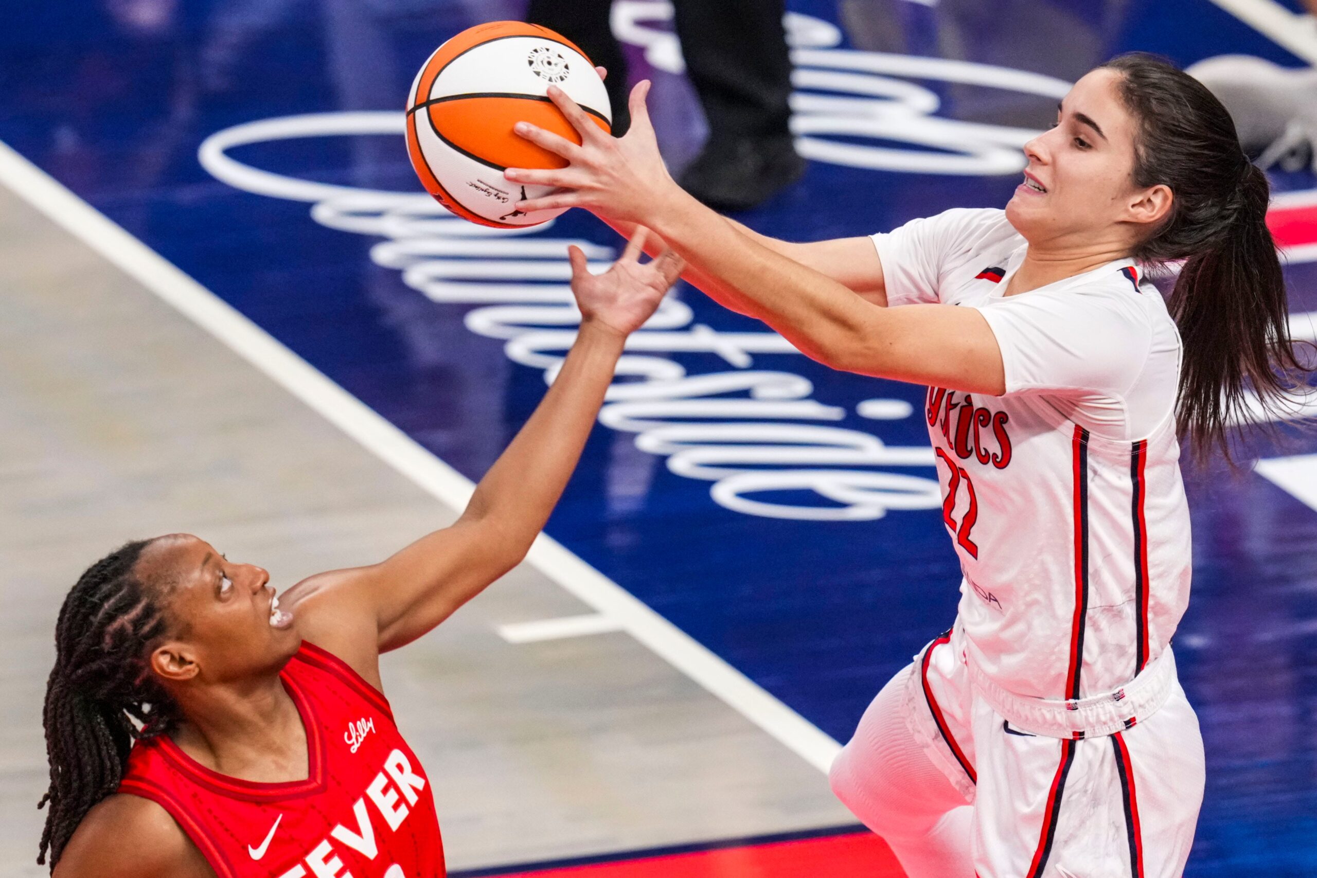 Indiana Fever guard Kelsey Mitchell (0) and Washington Mystics guard Sonia Citron (22) go for the ball Friday, Aug. 15, 2025, during a game between the Indiana Fever and the Washington Mystics at Gainbridge Fieldhouse in Indianapolis.