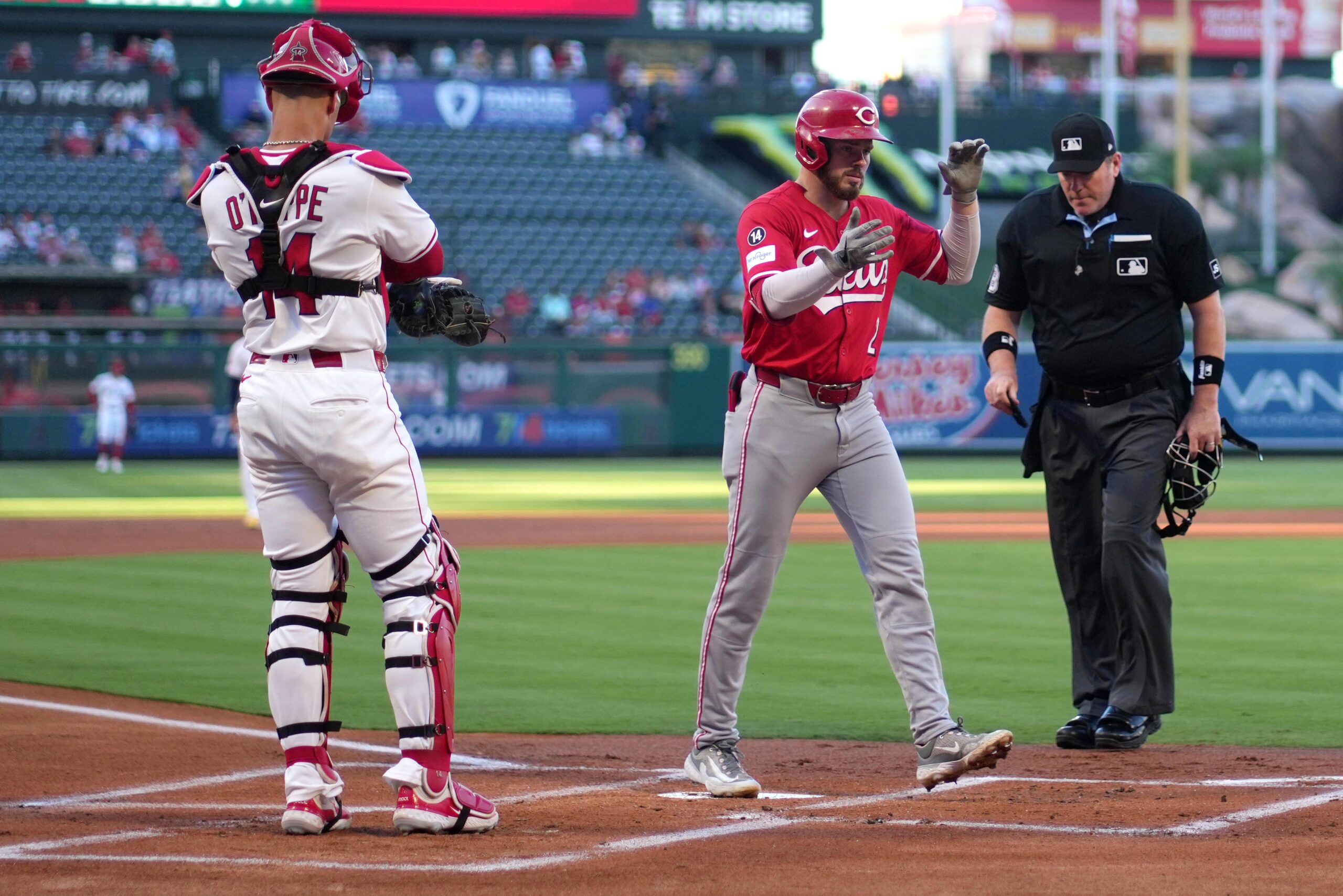 Aug 18, 2025; Anaheim, California, USA; Cincinnati Reds designated hitter Gavin Lux (2) crosses home plate after hitting a two-run home run in the first inning as Los Angeles Angels catcher Logan O'Hoppe (14) and home plate umpire Chris Conroy watch at Angel Stadium. Mandatory Credit: Kirby Lee-Imagn Images