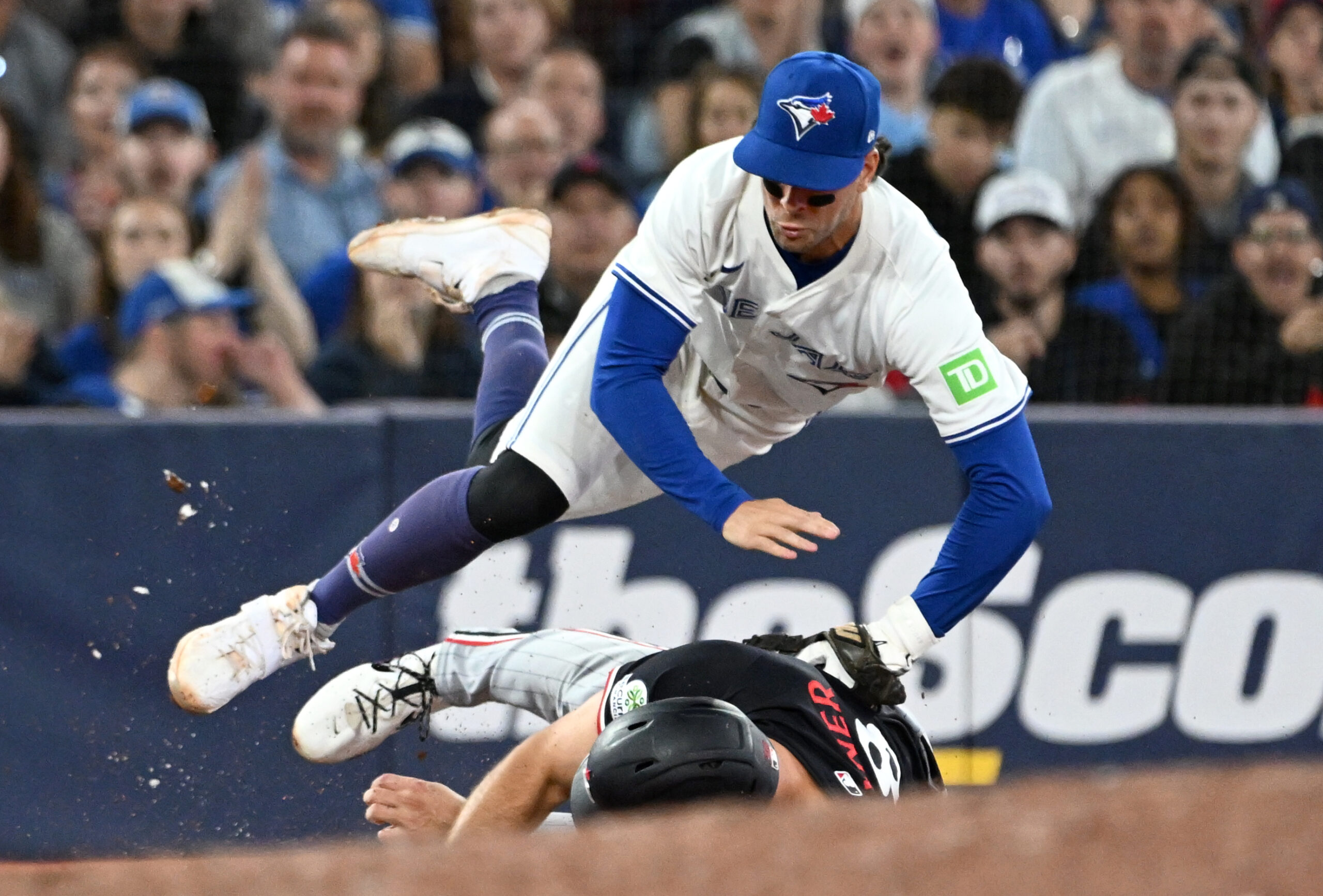 Aug 26, 2025; Toronto, Ontario, CAN;  Toronto Blue Jays third baseman Ernie Clement (22) is upended after tagging out Minnesota Twins right fielder Matt Wallner (38) in the eighth inning at Rogers Centre. Mandatory Credit: Dan Hamilton-Imagn Images