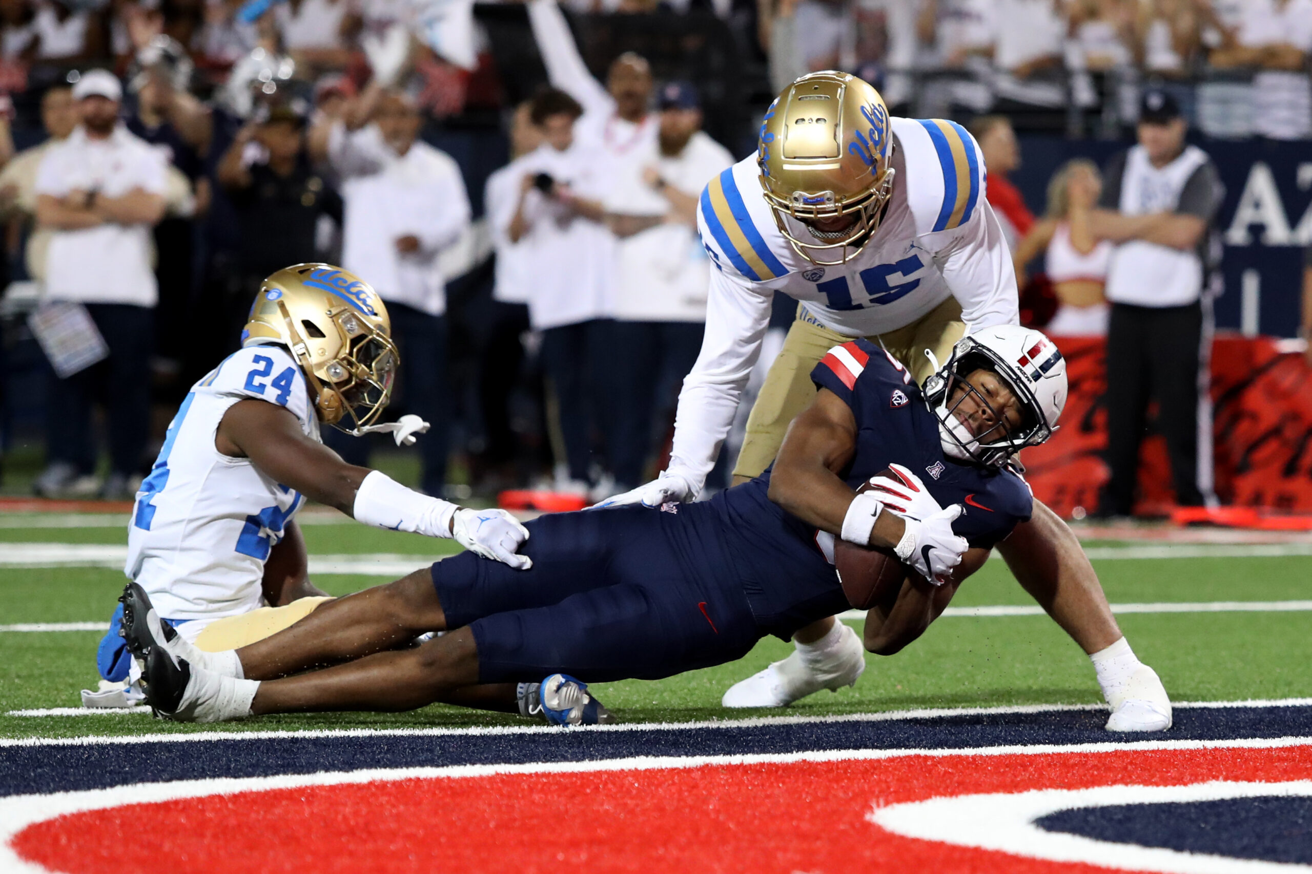 Nov 4, 2023; Tucson, Arizona, USA; Arizona Wildcats wide receiver Montana Lemonious-Craig #5 dives into the endzone against UCLA Bruins defensive back Jaylin Davies #24 and defensive lineman Laiatu Latu #15  during the first half at Arizona Stadium. Mandatory Credit: Zachary BonDurant-Imagn Images