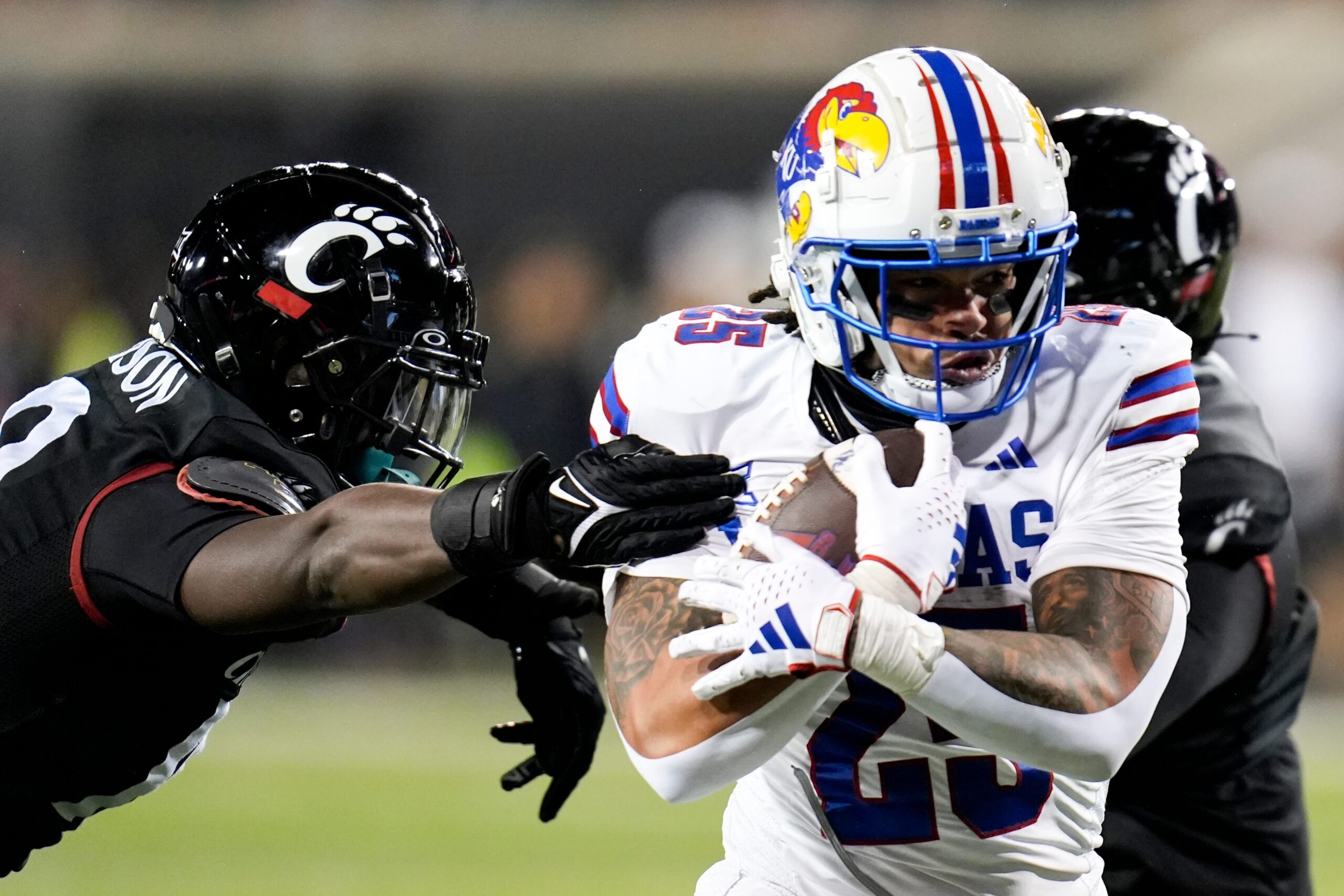 Kansas Jayhawks running back Dylan McDuffie (25) guards the ball from ensuing Cincinnati Bearcats as he runs down the field during the NCAA college football game between the Cincinnati Bearcats and Kansas Jayhawks on Saturday, Nov. 25, 2023, at Nippert Stadium in Cincinnati. Kansas won 49-16.