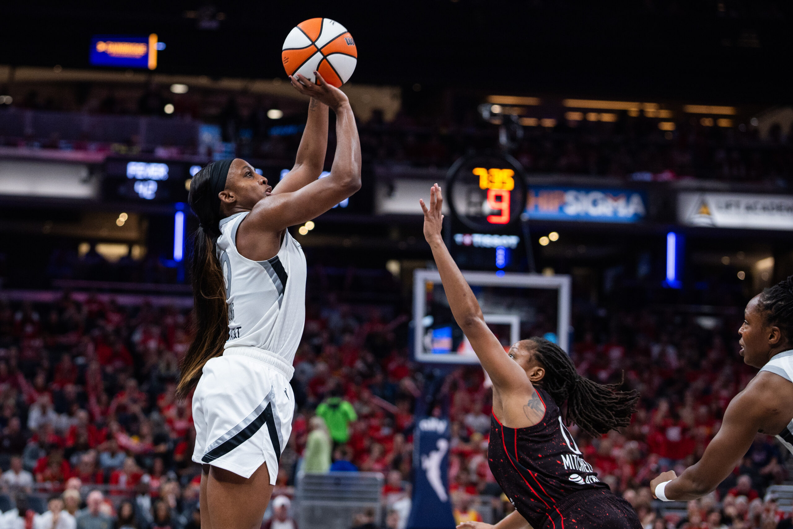 Sep 26, 2025; Indianapolis, Indiana, USA; Las Vegas Aces guard Jackie Young (0) shoots the ball while Indiana Fever guard Kelsey Mitchell (0) defends during game three of the second round for the 2025 WNBA Playoffs at Gainbridge Fieldhouse. Mandatory Credit: Trevor Ruszkowski-Imagn Images