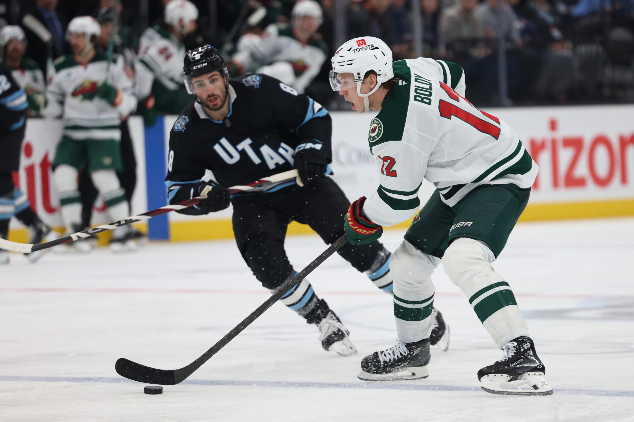 Feb 27, 2025; Salt Lake City, Utah, USA; Minnesota Wild left wing Matt Boldy (12) moves the puck against Utah Hockey Club center Nick Schmaltz (8) during the third period at Delta Center. Mandatory Credit: Rob Gray-Imagn Images
