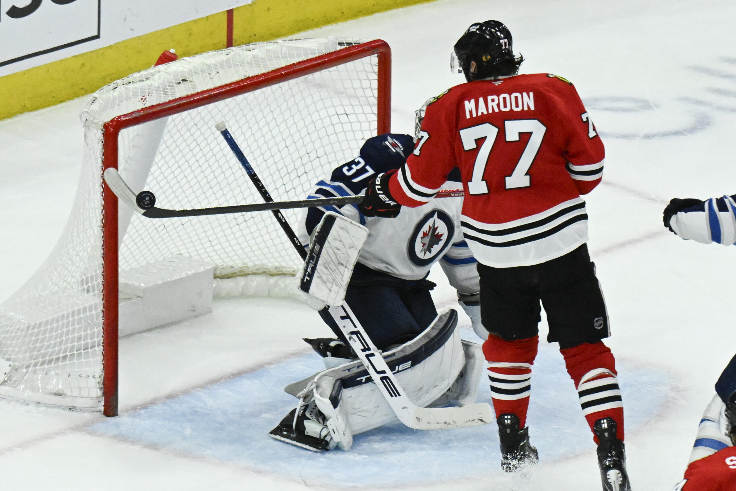 Apr 12, 2025; Chicago, Illinois, USA;  Chicago Blackhawks left wing Patrick Maroon (77) rises a shot against Winnipeg Jets goaltender Connor Hellebuyck (37) during the third period at United Center. Mandatory Credit: Matt Marton-Imagn Images