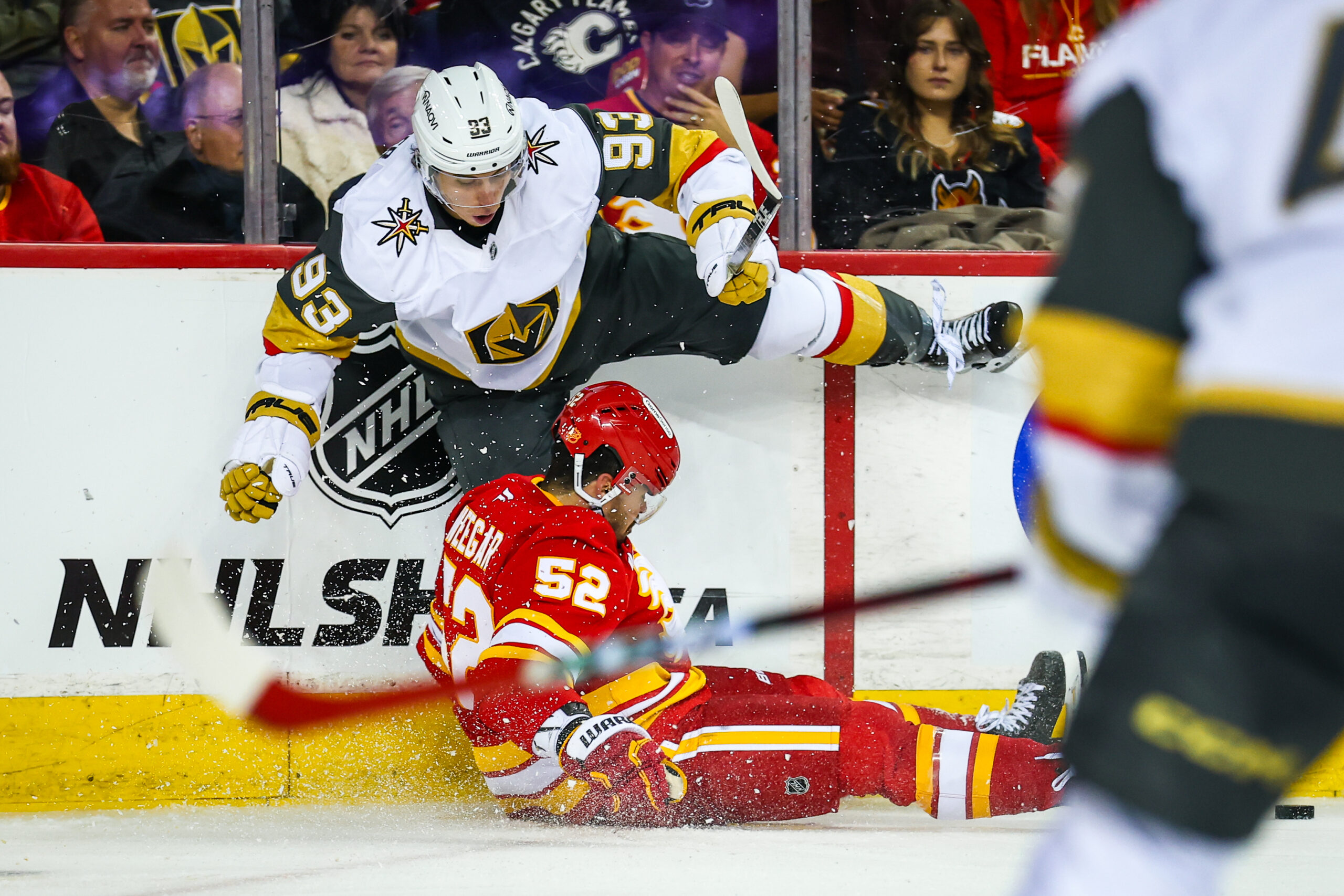 Oct 14, 2025; Calgary, Alberta, CAN; Calgary Flames defenseman Mackenzie Weegar (52) and Vegas Golden Knights right wing Mitch Marner (93) battles for the puck during the third period at Scotiabank Saddledome. Mandatory Credit: Sergei Belski-Imagn Images