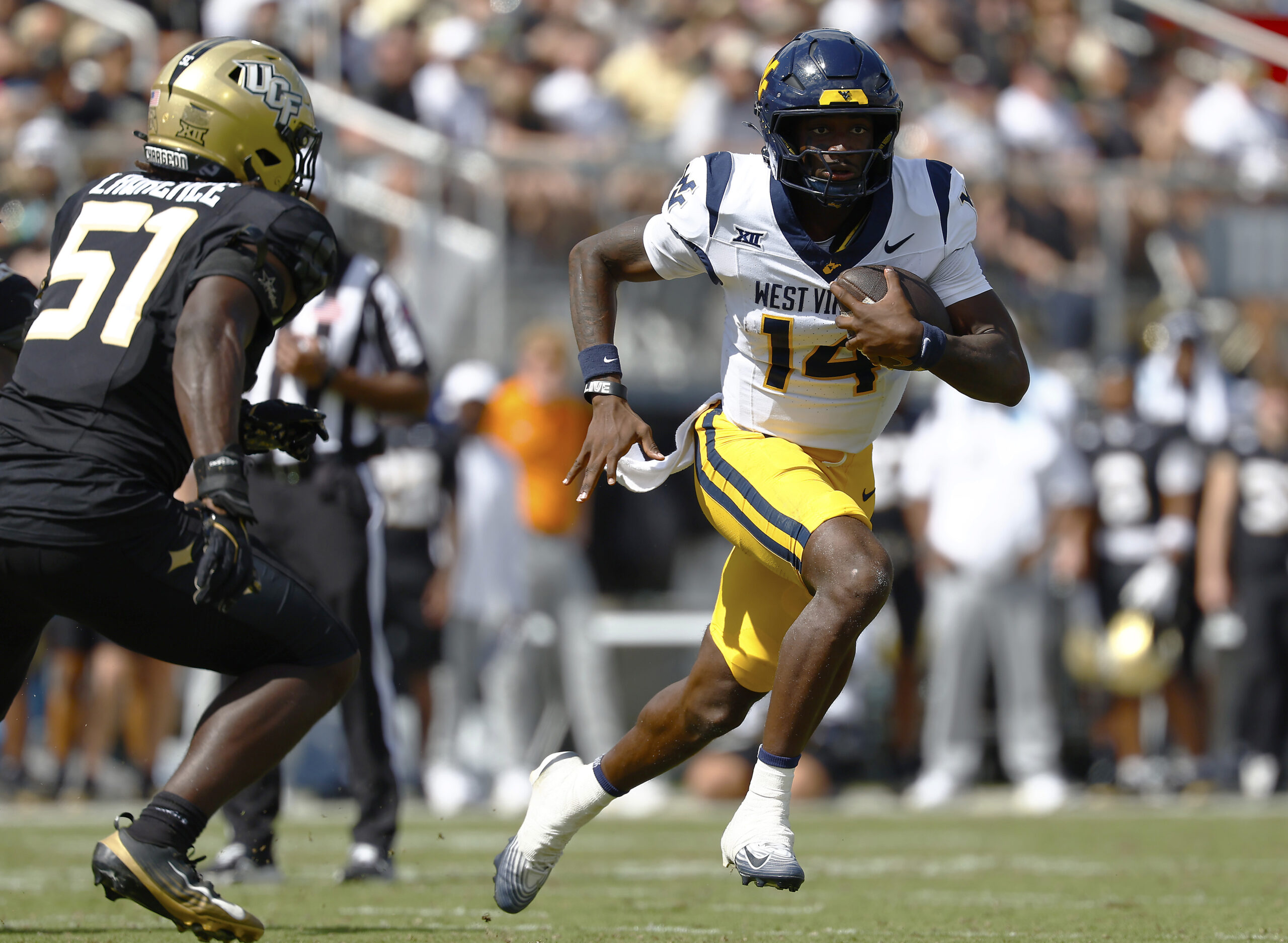 Oct 18, 2025; Orlando, Florida, USA; West Virginia Mountaineers quarterback Khalil Wilkins (14) runs the ball for a touchdown in the first half against the Central Florida Knights at Acrisure Bounce House. Mandatory Credit: Russell Lansford-Imagn Images