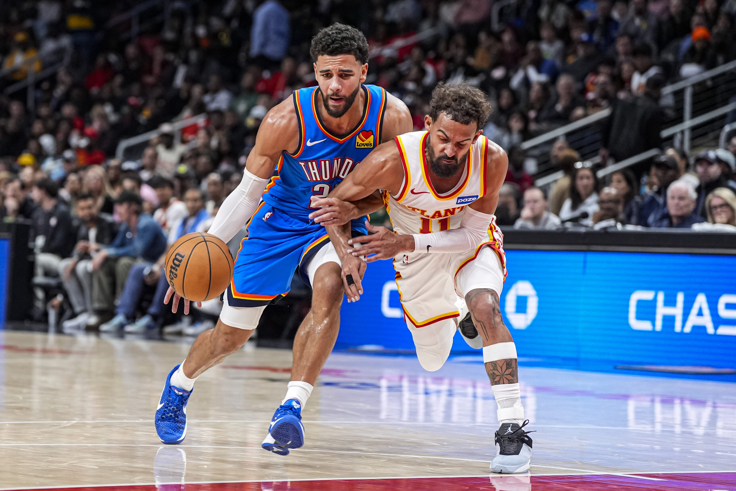 Oct 25, 2025; Atlanta, Georgia, USA; Oklahoma City Thunder guard Ajay Mitchell (25) tries to dribble past Atlanta Hawks guard Trae Young (11) during the second half at State Farm Arena. Mandatory Credit: Dale Zanine-Imagn Images